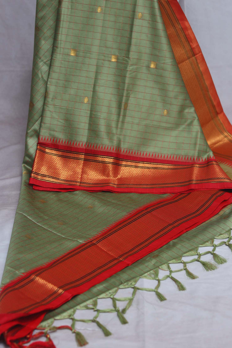 Light green semi silk saree with orange temple border, with stitched blouse