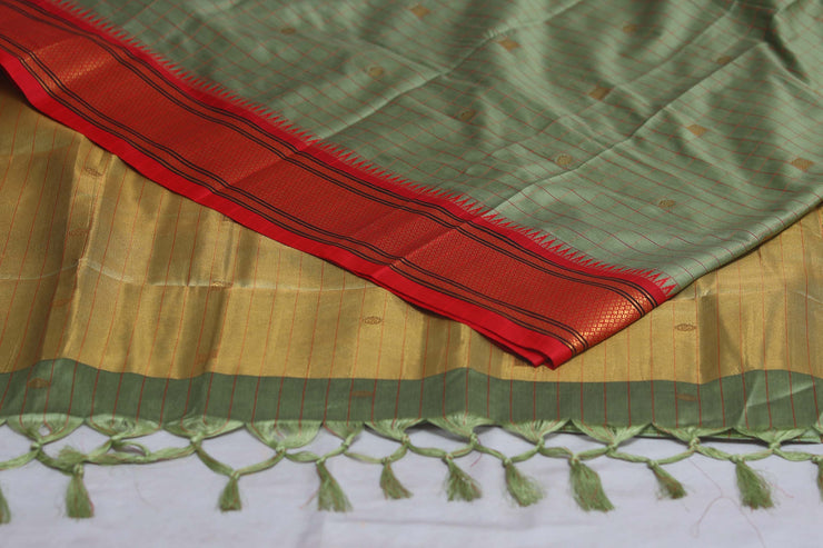 Light green semi silk saree with orange temple border, with stitched blouse